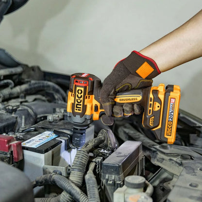 A person wearing a brown and black work glove uses a cordless impact driver with an orange and black battery pack on a car engine bay.